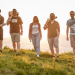 Gruppenfoto von BAM Berchtesgaden Akustik Musik. Mit den Instrumenten über die Schulter gehen die 5 Musikanten über eine Alpenwiese.